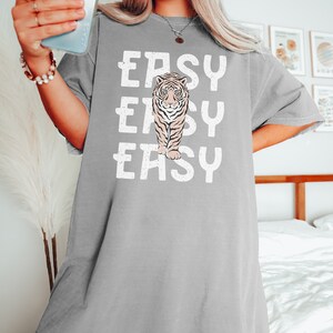 Peut inclure: T-shirt gris surdimensionn&eacute; avec un motif blanc d'un tigre et le mot "EASY" r&eacute;p&eacute;t&eacute; trois fois.
