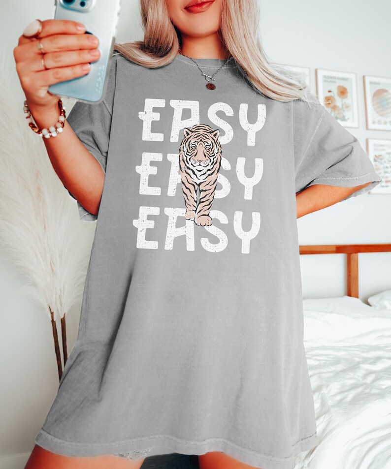 Peut inclure: T-shirt gris surdimensionn&eacute; avec un motif blanc d'un tigre et le mot "EASY" r&eacute;p&eacute;t&eacute; trois fois.