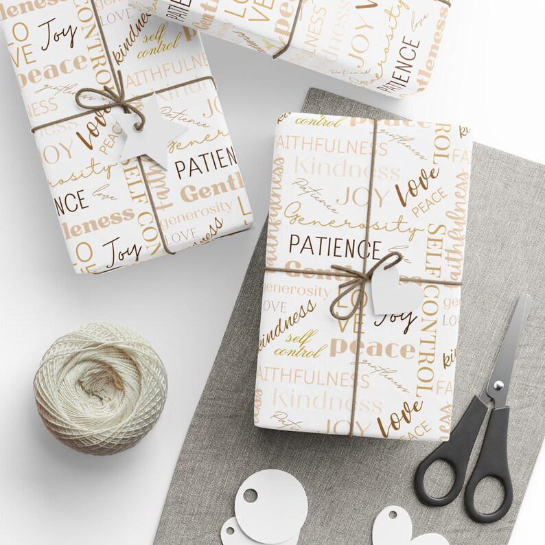 Puede incluir: Tres cajas de regalo blancas envueltas en papel marr&oacute;n y dorado con palabras como "amor", "alegr&iacute;a", "paz", "paciencia", "amabilidad", "generosidad" y "autocontrol". Las cajas est&aacute;n atadas con cuerda y tienen peque&ntilde;as etiquetas de regalo blancas adjuntas.