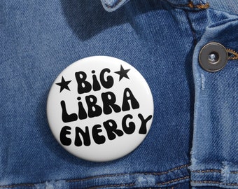 May include: White button with black text that reads "*BIG LIBRA ENERGY*" with two stars on either side of the word "BIG".