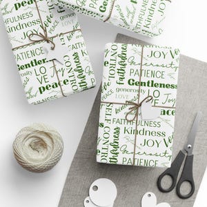 Puede incluir: Tres cajas de regalo blancas envueltas en papel blanco con texto verde. El texto en las cajas incluye palabras como "paz", "alegr&iacute;a", "bondad", "paciencia", "mansedumbre", "fidelidad", "generosidad", "amor" y "dominio propio".