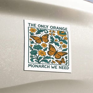May include: A white rectangular sticker with the text "THE ONLY ORANGE MONARCH WE NEED" and a design featuring orange butterflies, yellow flowers, and teal leaves. The sticker is affixed to the back of a vehicle.
