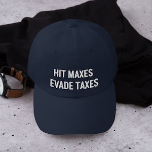 Könnte beinhalten: Eine marineblaue Baseballkappe mit weiß gesticktem Text, der "HIT MAXES EVADE TAXES" lautet.