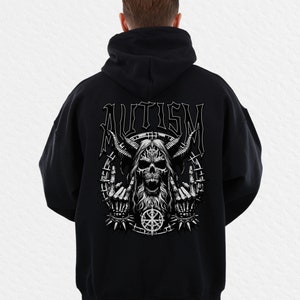 Puede incluir: Sudadera con capucha negra con un gráfico blanco de una calavera con cuernos, una larga barba y la palabra "AUTISM" encima. La calavera está rodeada por un círculo con un borde puntiagudo y un símbolo. La sudadera tiene capucha y mangas largas.