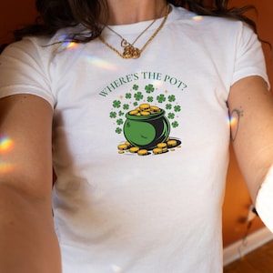 以下が含まれることがあります： 緑の金の壺とクローバーが描かれた白いTシャツで、"Where's the pot?"という文字が書かれています