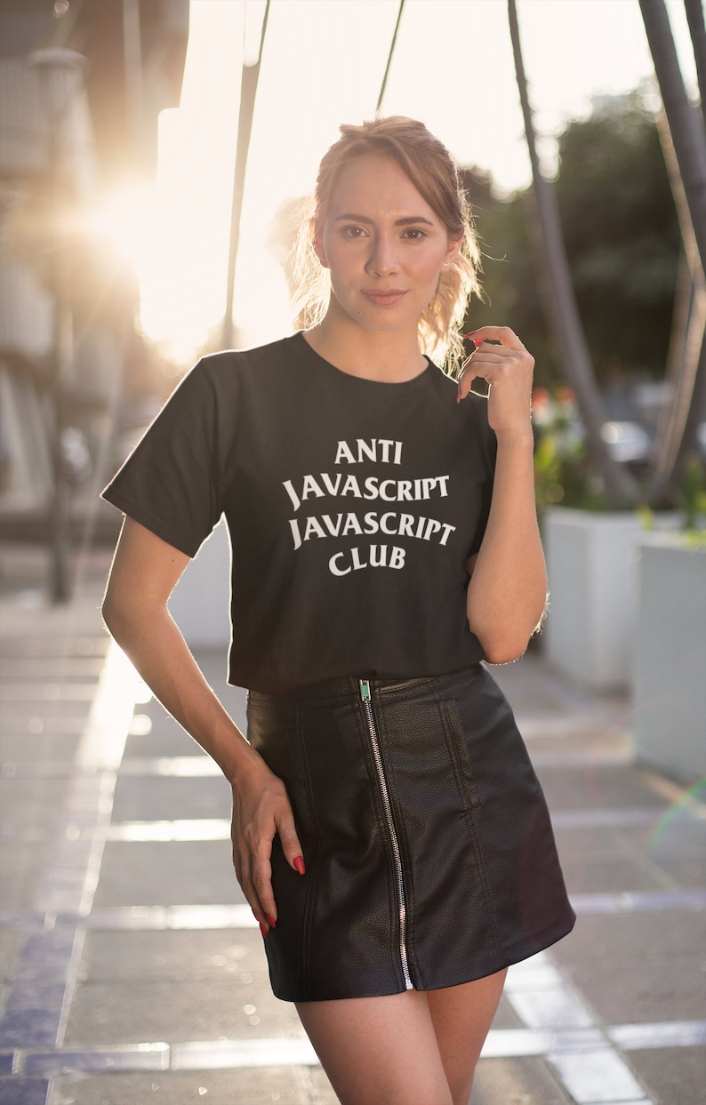 May include: A woman wearing a black cropped t-shirt with the text "ANTI JAVASCRIPT JAVASCRIPT CLUB" in white. She is wearing a black leather skirt and has her hair pulled back.