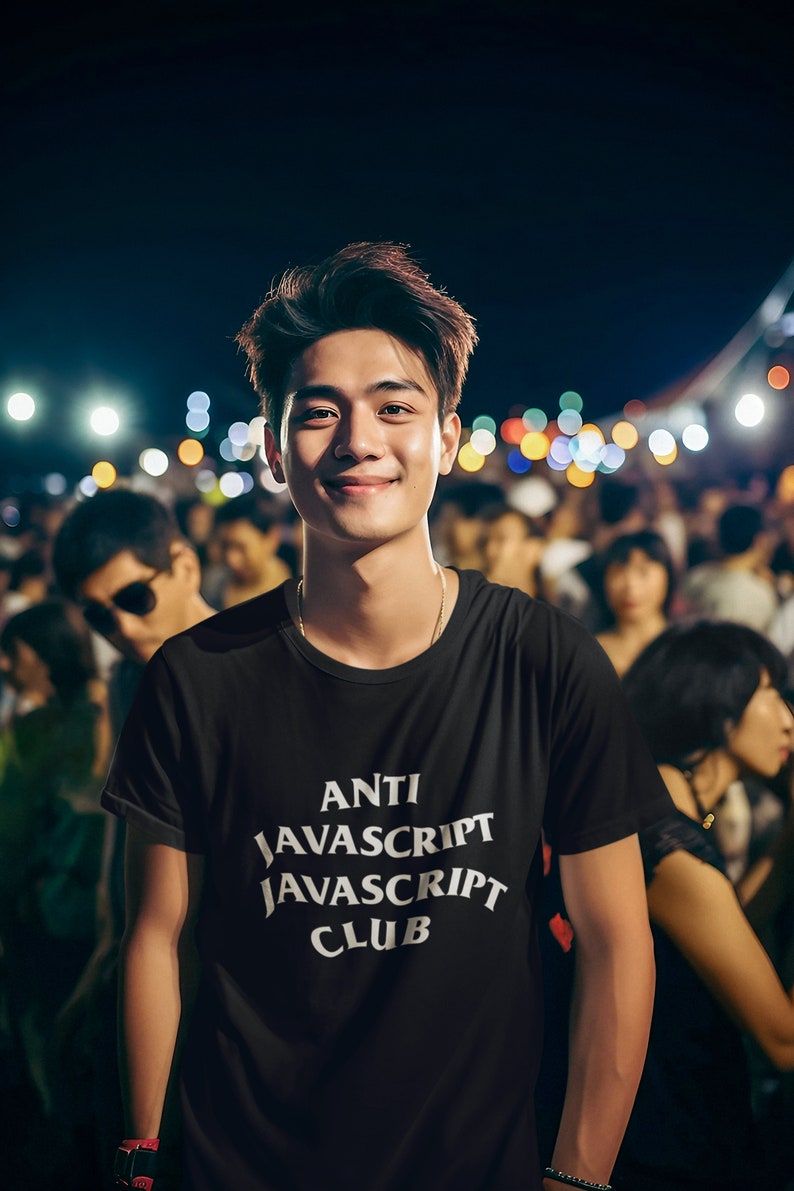 May include: A man wearing a black t-shirt with the text "ANTI JAVASCRIPT JAVASCRIPT CLUB" in white. He is standing in a crowd of people at a concert or event.