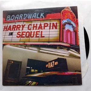 May include: Album cover for "Boardwalk" featuring "Harry Chapin in Sequel." The cover art displays a vintage neon sign with the album title and artist's name. The design includes a theatre marquee with red, pink, and white lights.