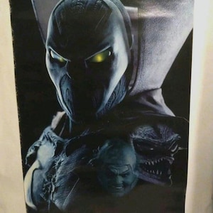May include: A black and white poster featuring a close-up of Spawn, a comic book superhero, with glowing green eyes. The poster has the word "SPAWN" printed at the bottom.