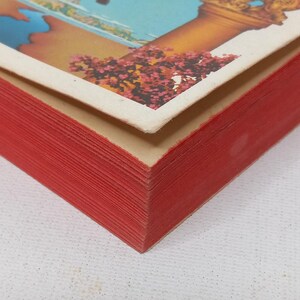 Puede incluir: Primer plano del lomo de un libro de tapa dura rojo. El libro est&aacute; hecho de muchas capas de papel, creando un aspecto texturizado.