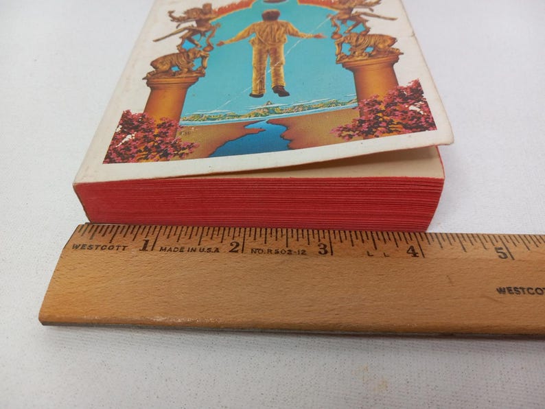 Puede incluir: Un libro de tapa dura rojo con una ilustraci&oacute;n colorida en la portada. La ilustraci&oacute;n representa a una persona de pie en una puerta con un cielo azul y agua en el fondo.