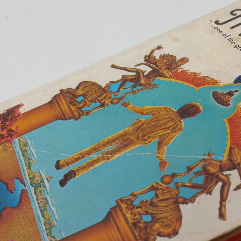 Puede incluir: Una portada de libro vintage con una ilustraci&oacute;n colorida de un hombre de pie en una plataforma con un cielo azul y nubes de fondo. El hombre lleva una camisa y pantalones marrones. Hay estatuas de personas y animales en la plataforma. El texto de la portada dice "...uno de los grandes"