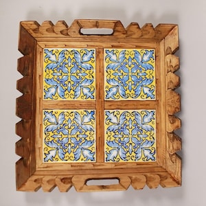 May include: Square wooden serving tray with four yellow and blue floral tile inserts. The tray has a carved wooden frame with handles and a decorative edge. A decorative piece for the home.