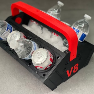 May include: A black and red cooler with a handle, labeled "V8", holds four beverage cans and three water bottles. The cooler is filled with ice.