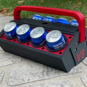 May include: Black and red toolbox-style cooler with a handle. The cooler has six slots for cans and the text "V8" on the side.