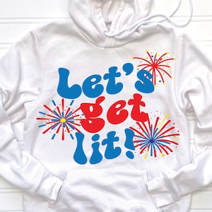 May include: White hooded sweatshirt with the text "Let's get lit!" in blue, red, and yellow lettering with firework graphics.