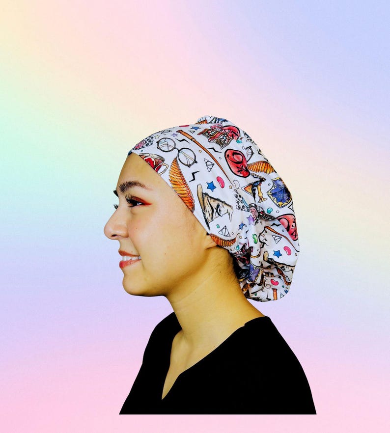 May include: A white cap with a colorful pattern featuring various illustrations. The cap is adorned with images of glasses, stars, and other whimsical designs. The cap is worn by a person wearing a black shirt.