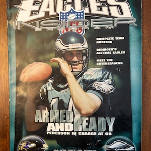 May include: An Eagles Insider Program magazine cover. The cover features a football player in a helmet, holding a football. Text includes "ARMED AND READY" and "PEDERSON IN CHARGE AT QB". The magazine also has the text "EAGLES INSIDER PROGRAM".