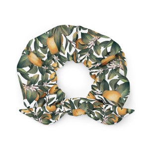 Op de afbeelding: Een witte scrunchie met een citroenboomprint. De scrunchie is gemaakt van stof en heeft een strik aan de bovenkant.
