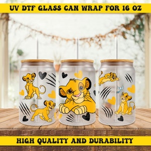 May include: Three clear glass 16 ounce cans with bamboo lids and yellow straws. Each can has a different image of Simba from The Lion King, with black hearts and claw marks. The text "UV DTF GLASS CAN WRAP FOR 16 OZ" is at the top of the image and "HIGH QUALITY AND DURABILITY" is at the bottom.