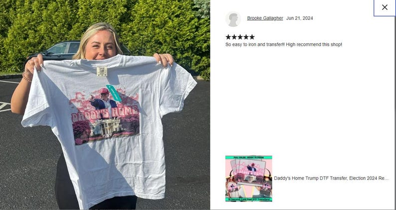 a woman holding up a t - shirt in front of a car