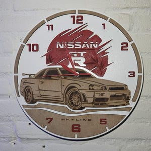 May include: A round wooden wall clock featuring a car design. The clock face is white with brown numerals and a red Nissan GT logo. The car is a detailed illustration of a Skyline GT-R.