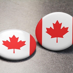 May include: Two round white buttons featuring a red maple leaf design, representing the Canadian flag.