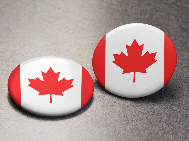 May include: Two round white buttons featuring a red maple leaf design, representing the Canadian flag.