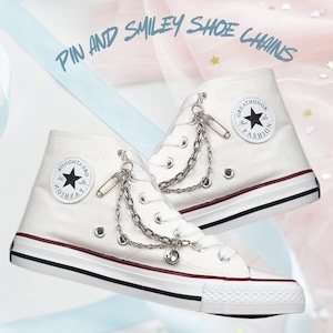 May include: White high-top sneakers with a black star and "GREAT HONOR FASHION" text on the side. The sneakers have silver chain and safety pin accents.