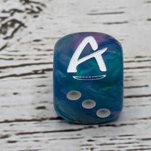 May include: A blue and green dice with white swirl pattern and white dots. The dice has a white letter 'A' on one side.