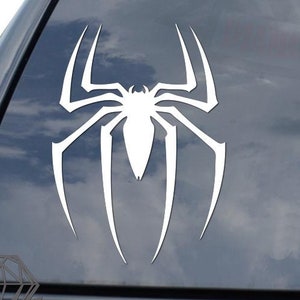May include: White spider silhouette decal on a black car window. The spider is stylized with long legs and a rounded body.