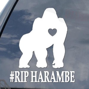 May include: White vinyl car sticker with a gorilla silhouette holding a heart in its hand. The text #RIP HARAMBE is below the gorilla.