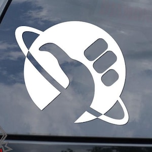May include: White vinyl sticker of a stylized fist giving a thumbs up, with a ring around it, on a black car window.