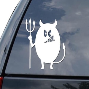 May include: White vinyl decal of a cartoon devil holding a trident. The devil has horns, a tail, and an angry expression. The decal is on the rear window of a black vehicle.