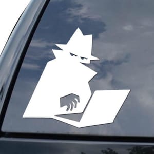 May include: White vinyl decal of a fedora-wearing figure working on a laptop. The decal is applied to the rear window of a black vehicle. A diamond-shaped logo is visible below the figure.