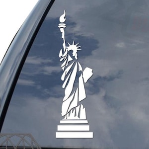 May include: White vinyl sticker of the Statue of Liberty on a black car window.