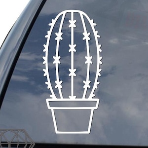 May include: White vinyl cactus sticker in a pot, applied to the rear window of a black vehicle. The cactus design features a series of vertical lines with small star-shaped details, creating a minimalist, botanical aesthetic.