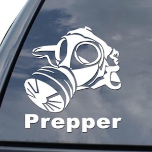 May include: White vinyl decal of a gas mask with the word "Prepper" in a bold, sans-serif font. The decal is affixed to the rear window of a black vehicle. The image also includes a diamond-shaped logo.