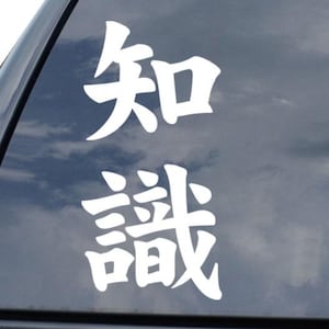 May include: White vinyl decal featuring the Japanese characters for "knowledge" on a car window. The decal is positioned vertically and is accompanied by a diamond-shaped logo at the bottom right.