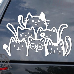 May include: White vinyl decal of a group of six cats with different expressions, some wearing glasses, on a black car window.