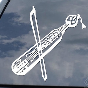 May include: White vinyl decal of a dental instrument and a crossed dental probe, applied to a car window. The design includes a detailed illustration of a dental tool with a curved handle and a probe. The decal is a decorative item.