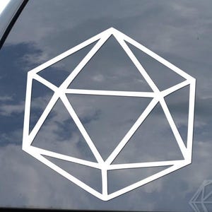 May include: A white, geometric icosahedron sticker, a 20-sided die, is affixed to the rear window of a black vehicle. The sticker is a simple outline, showcasing the shape's facets. The image suggests a theme related to tabletop gaming or role-playing.