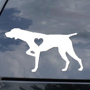 May include: White vinyl decal of a German Shorthaired Pointer dog with a heart in its chest. The decal is on the back window of a black car.