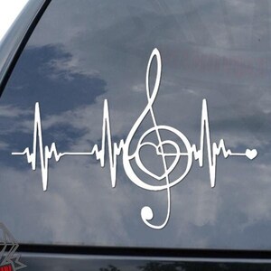 May include: White vinyl decal of a music note with a heart in the center, with a heartbeat line on either side. The decal is on the back window of a car.