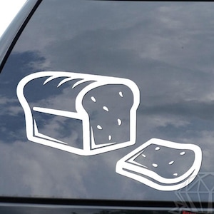 May include: White vinyl decal of a loaf of bread and a single slice. The bread has a rounded top with curved lines and small circular details. The slice is next to the loaf, also with circular details.