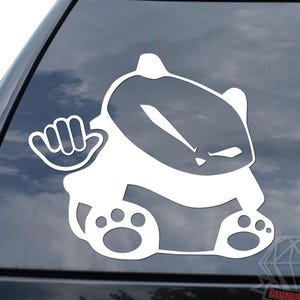May include: White vinyl car decal featuring a cartoon badger with a fist and paw prints. The badger has an angry expression. The decal is applied to the rear window of a black vehicle.