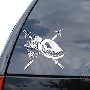 May include: White vinyl decal of a fish skeleton with crossed fishing spears. The fish has a toothy grin and is facing right.