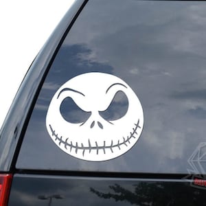 May include: White vinyl decal of Jack Skellington's face from the movie The Nightmare Before Christmas. The decal is on a black car window.