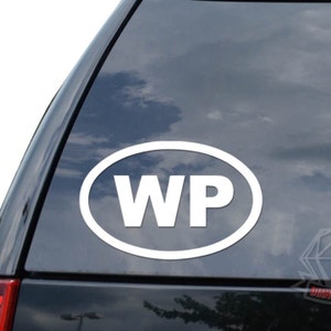 May include: White oval sticker with the letters "WP" in a white oval on a black car window.
