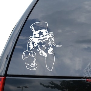 May include: White vinyl sticker of Uncle Sam giving the middle finger. The sticker is on a car window.